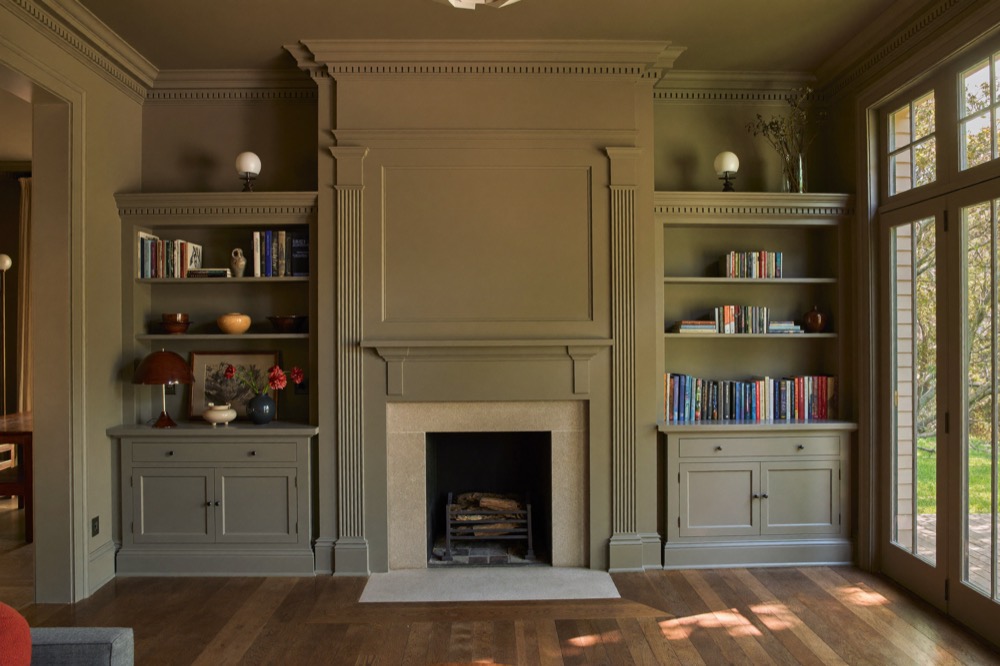 Painted built-in bookcases and cabinets either side of a fireplace with fluted pilasters