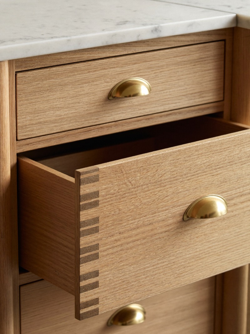 White oak drawers with brass cup pulls, one drawer open to show its jointed corner