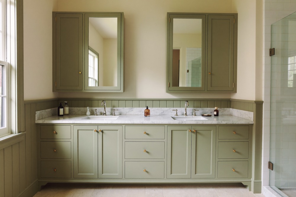 A long sage-green painted double vanity with a marble top and two matching mirrored medicine cabinets